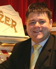 Image of a smiling Kevin Grunill with the edge of a Wurlitzer in the background to the left
