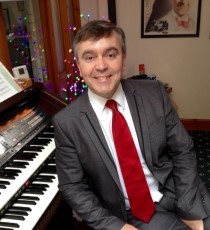 Image of a smiling Nicolas Martin with a black organ keyboard behind him